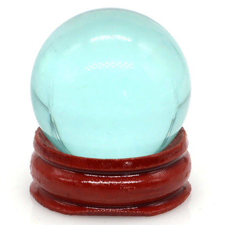 Turquoise crystal ball on a red wooden stand against a white background