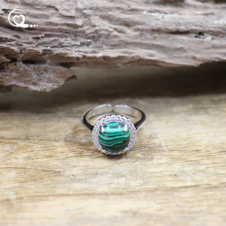 Silver ring with a green gemstone on a wooden surface