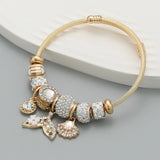 Gold bracelet with decorative beads and charms on a gray surface