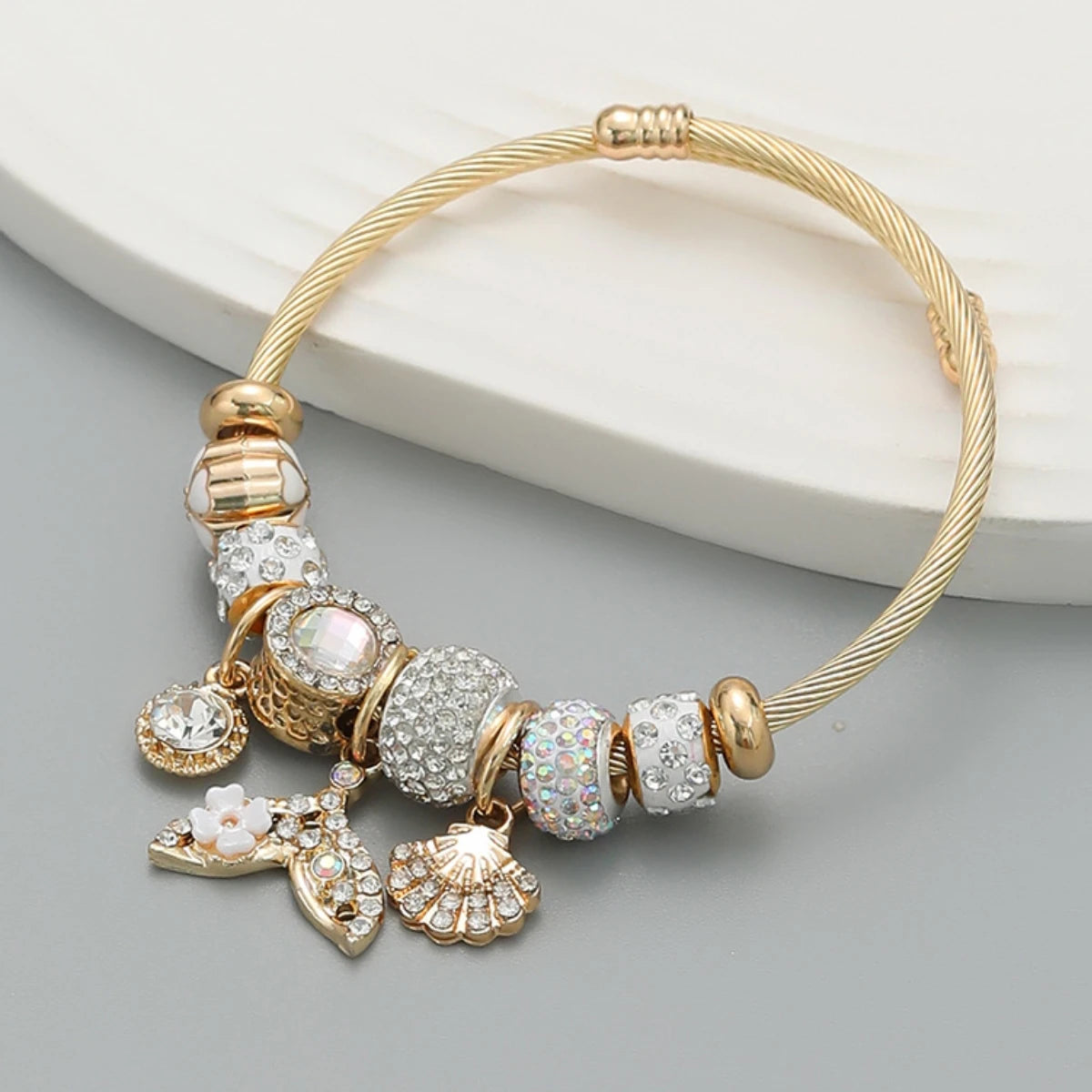 Gold bracelet with decorative beads and charms on a gray surface