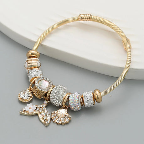 Gold bracelet with decorative beads and charms on a gray surface
