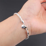 Silver bracelet on a wrist against a dark background