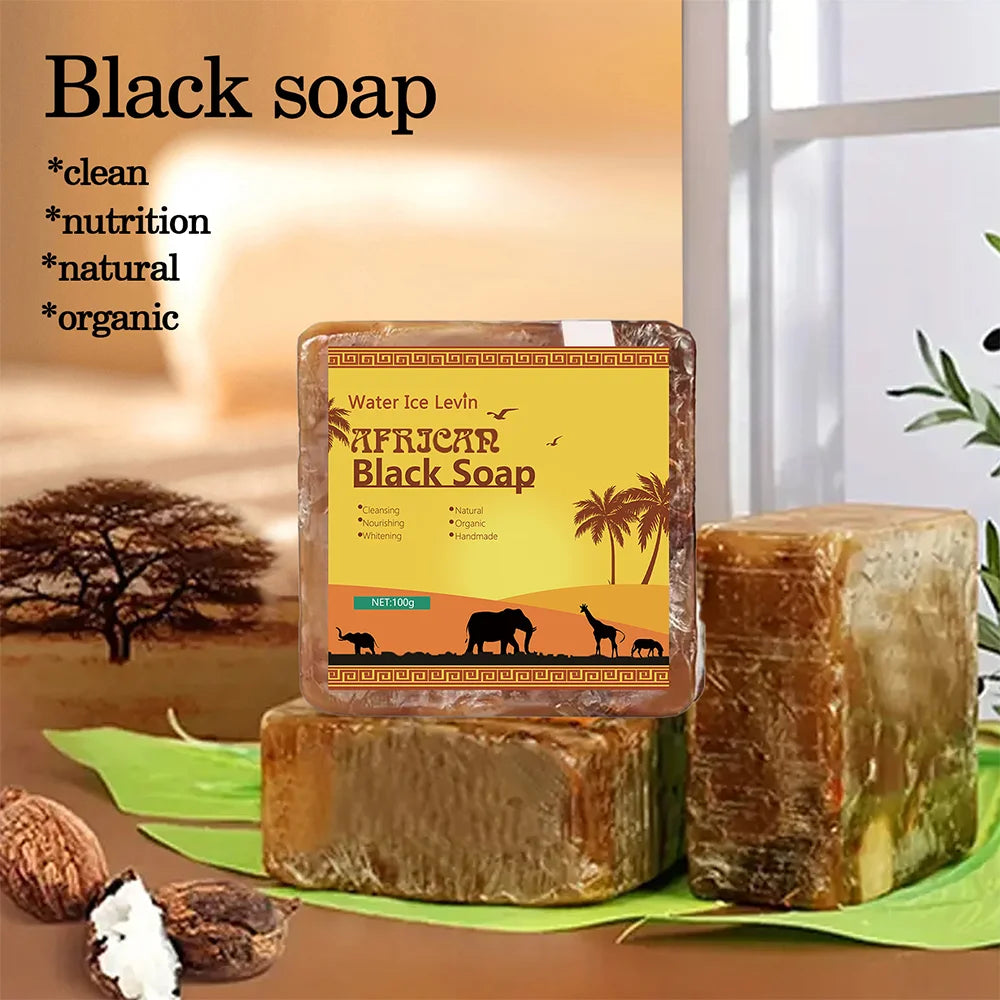 African Black Soap bar with packaging featuring a scenic label, placed on a green leaf with a blurred natural background.