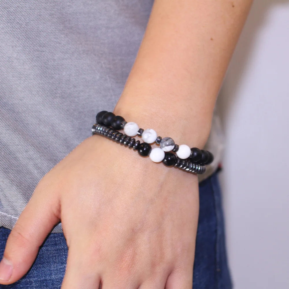 Close-up of a hand wearing a beaded bracelet with black, white, and gray beads.
