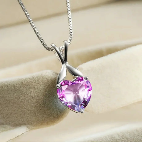 Silver necklace with a pink heart-shaped gemstone on a beige background