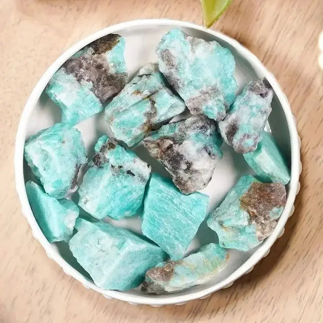 Turquoise crystal pieces in a white bowl on a wooden surface