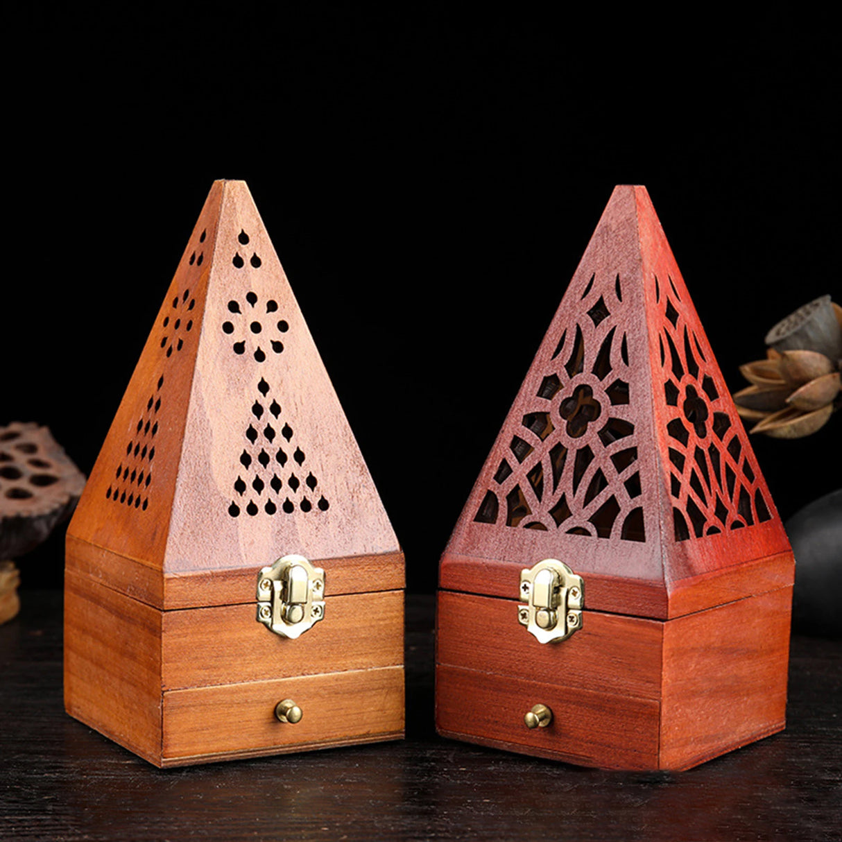 Two wooden pyramid-shaped incense burners with intricate designs on a dark background.