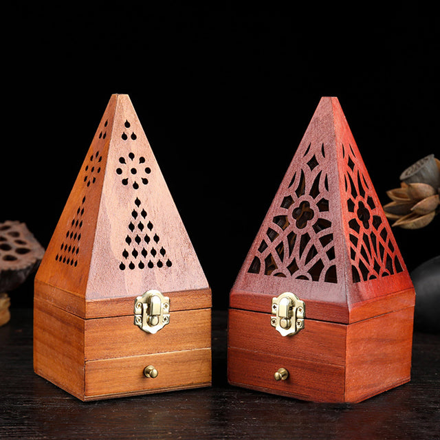 Two wooden pyramid-shaped incense burners with intricate designs on a dark background.
