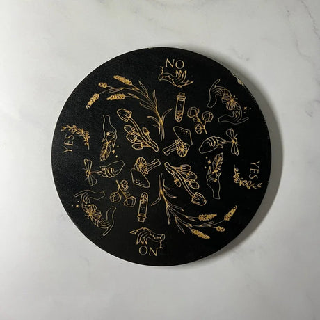 Black circular coaster with gold designs and text on a white background