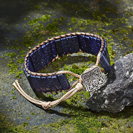 Navy blue bracelet with braided design and decorative clasp on a stone surface