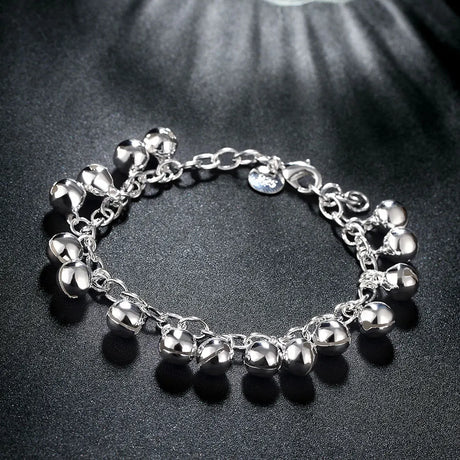 Silver bracelet with various charms on a dark surface