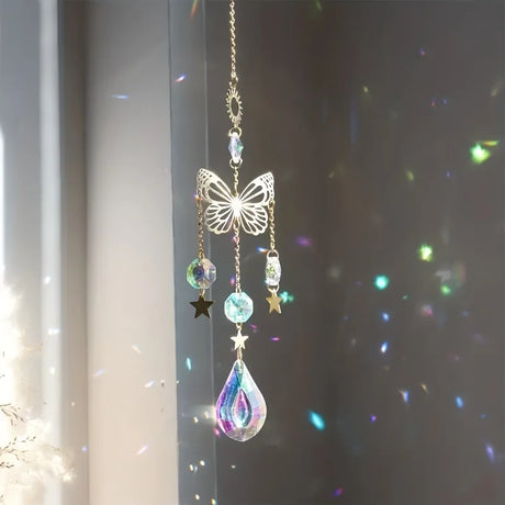 Decorative hanging ornament with butterfly and teardrop design in front of a window.