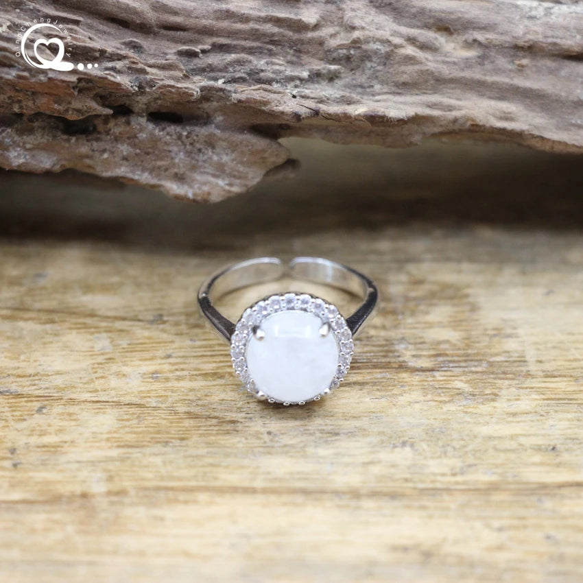 Silver ring with a white stone on a wooden surface