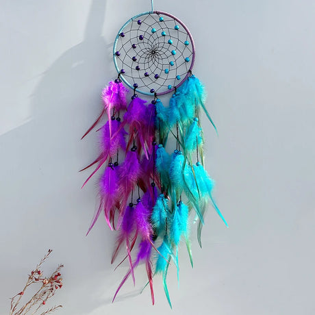 Colorful dreamcatcher with purple and blue feathers on a white background
