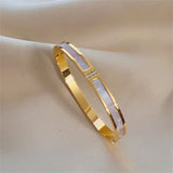 Gold bracelet with a central pearl-like stone on a beige fabric background