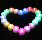 Colorful LED candles arranged in a heart shape on a black background
