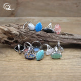 Set of silver rings with colorful gemstones on a wooden surface