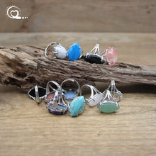 Set of silver rings with colorful gemstones on a wooden surface
