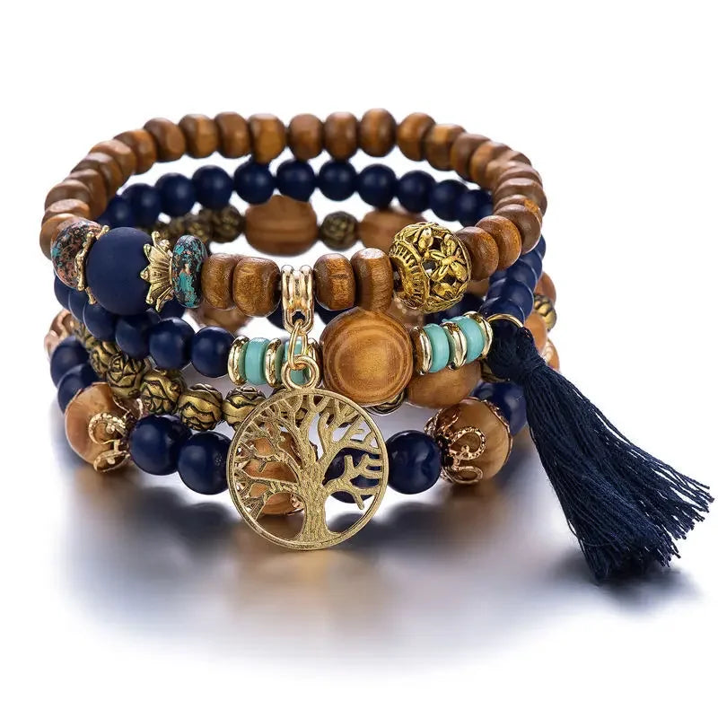 Stack of beaded bracelets with tree of life charm on a white background