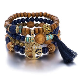 Stack of beaded bracelets with tree of life charm on a white background