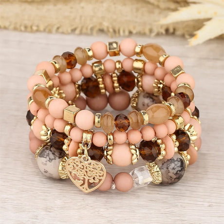 Set of beaded bracelets with gold accents and a heart charm on a neutral background