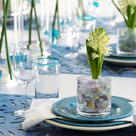 Decorative table setting with a glass vase containing flowers on a blue plate.