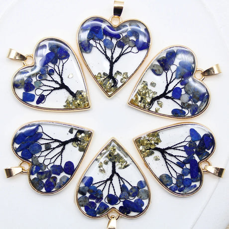 Heart-shaped pendants with tree design and blue and green elements on a white background