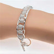 Silver bracelet on a wrist with a plain background