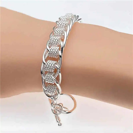 Silver bracelet on a wrist with a plain background