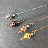 Three necklaces with decorative pendants on a gray surface