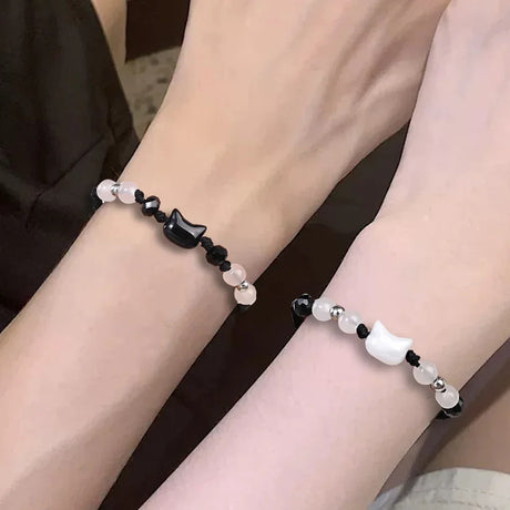 Two beaded bracelets on wrists with a neutral background