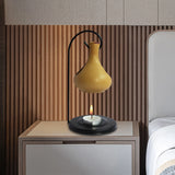 Yellow lamp with a candle on a nightstand against a wooden wall.