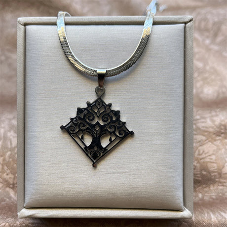 Silver necklace with a black filigree pendant on a textured surface