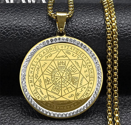 Gold pendant with intricate design and chain on a textured black background