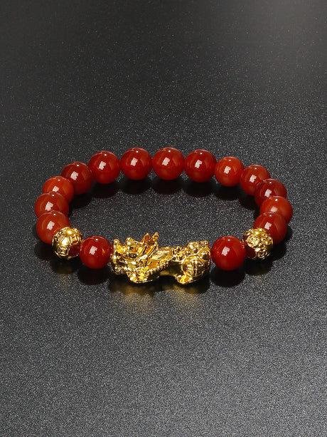 Bracelet with red beads and gold accents on a dark background