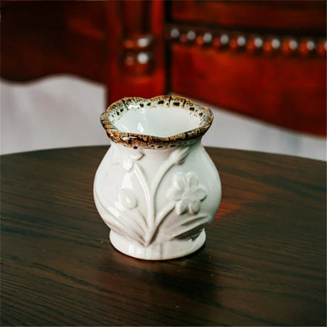 White ceramic vase with floral designs on a wooden surface