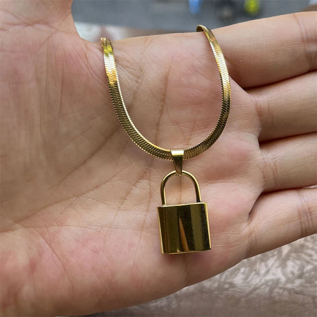 Gold padlock necklace held in a hand