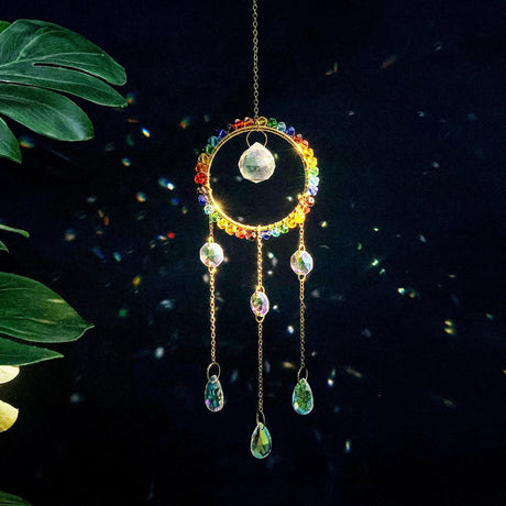 Colorful crystal wind chime with green leaves on a dark background