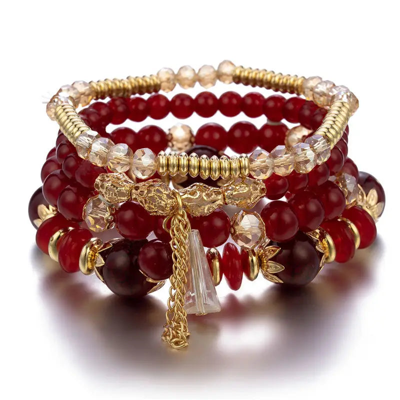 Stack of red beaded bracelets with gold accents on a white background