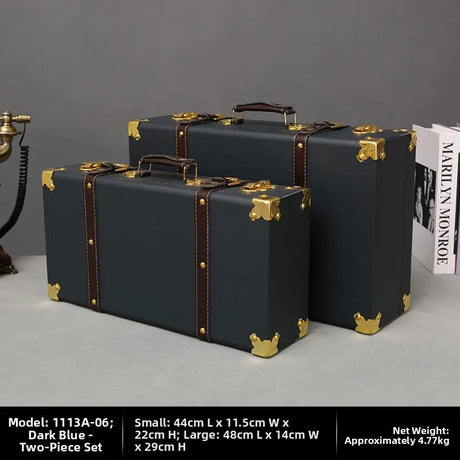 Two dark blue suitcases with gold accents on a gray surface.