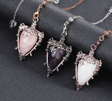 Three ornate pendants with heart-shaped gemstones on a dark surface, with 'Cala Jewelry' logo.
