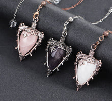 Three ornate pendants with heart-shaped gemstones on a dark surface, with 'Cala Jewelry' logo.