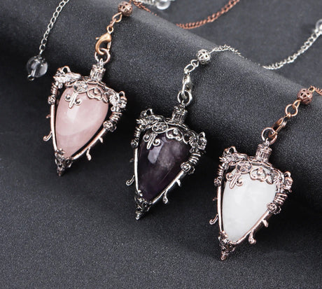 Three ornate pendants with heart-shaped gemstones on a dark surface, with 'Cala Jewelry' logo.