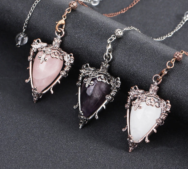 Three ornate pendants with heart-shaped gemstones on a dark surface, with 'Cala Jewelry' logo.