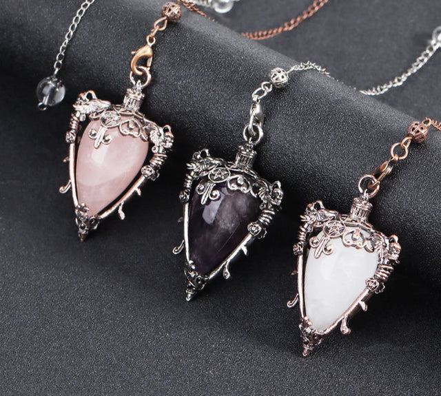Three ornate pendants with heart-shaped gemstones on a dark surface, with 'Cala Jewelry' logo.
