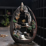 Decorative sculpture of a mountain scene with a waterfall and building on a dark background