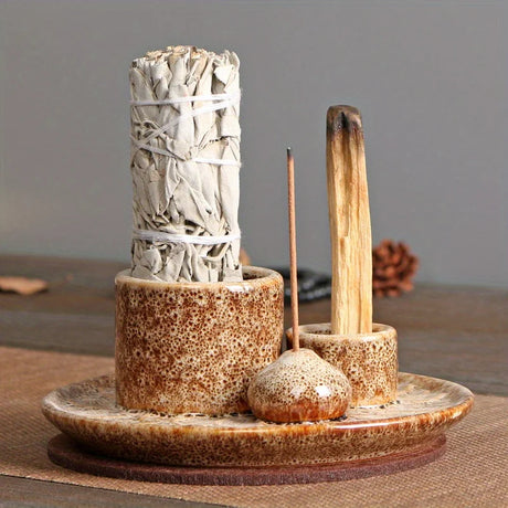 Ceramic holder with white sage bundle, wooden matches, and small container on a wooden surface.