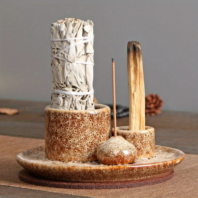 Ceramic holder with white sage bundle, wooden matches, and small container on a wooden surface.