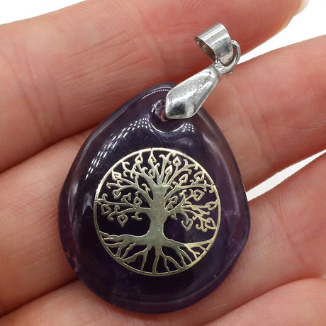 Purple pendant with silver 'Tree of Life' design held in a hand