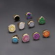 Collection of colorful rings with gold bands on a gray background